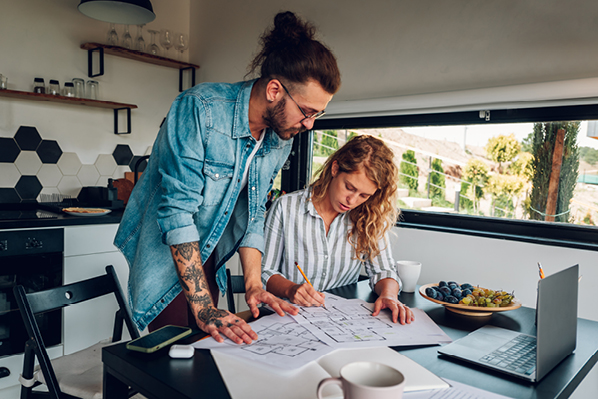 a couple in their 30s looking at paperwork at their kitchen table